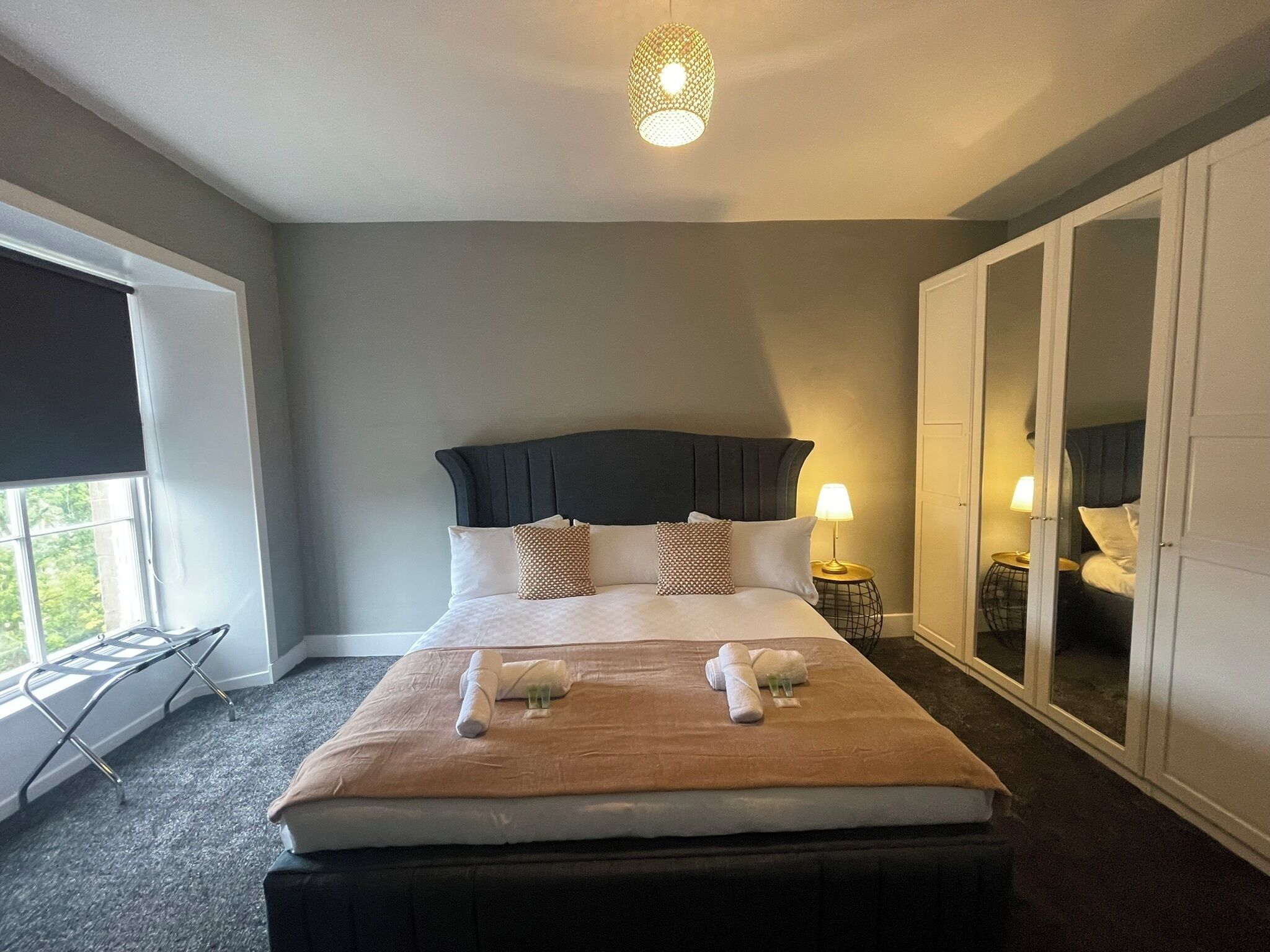 Une chambre d’hôtel avec un lit, deux lampes de chevet, une fenêtre donnant sur un paysage agréable et une armoire.