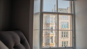 A room with a large window, a plush chair, and a view of buildings outside. - The West Nest For Six - Pass the Keys (Glasgow)
