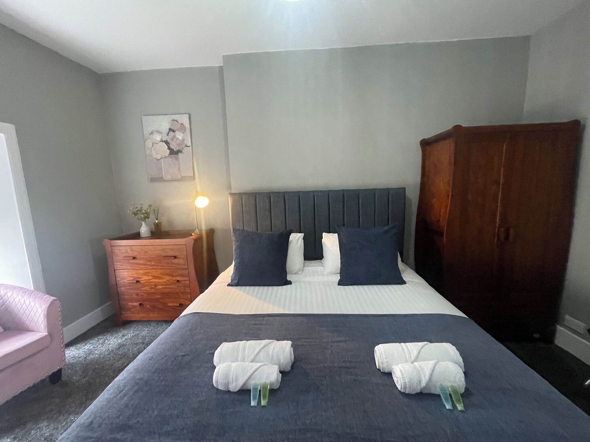 Une chambre à coucher comprenant un lit, une commode, une chaise et une armoire.