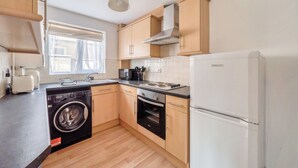 Eine kompakte Küche mit Waschmaschine, Backofen, Mikrowelle und Kühlschrank.