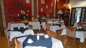 Restaurante com mesas postas para refeições, um espaço para café e diversas decorações nas paredes.