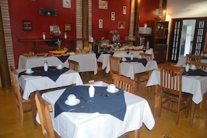 Un restaurante con mesas dispuestas para comer, una estación de café y diversas decoraciones en las paredes.