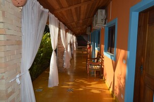 Un pasillo con techo de madera, un banco y una puerta con marco azul.