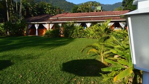 Um edifício com telhado de telhas, rodeado por vegetação exuberante e um gramado bem cuidado.