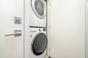 A laundry room with two stacked washing machines, a door with a handle, and a control panel. - Elevated 2BR Lakeview Escape w/ Modern Amenities Near Harrison Lake (Harrison Hot Springs)