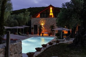A stone building with a pool, surrounded by umbrellas and lounge chairs. - MASHTRA - The Olive House (Ulcinj)