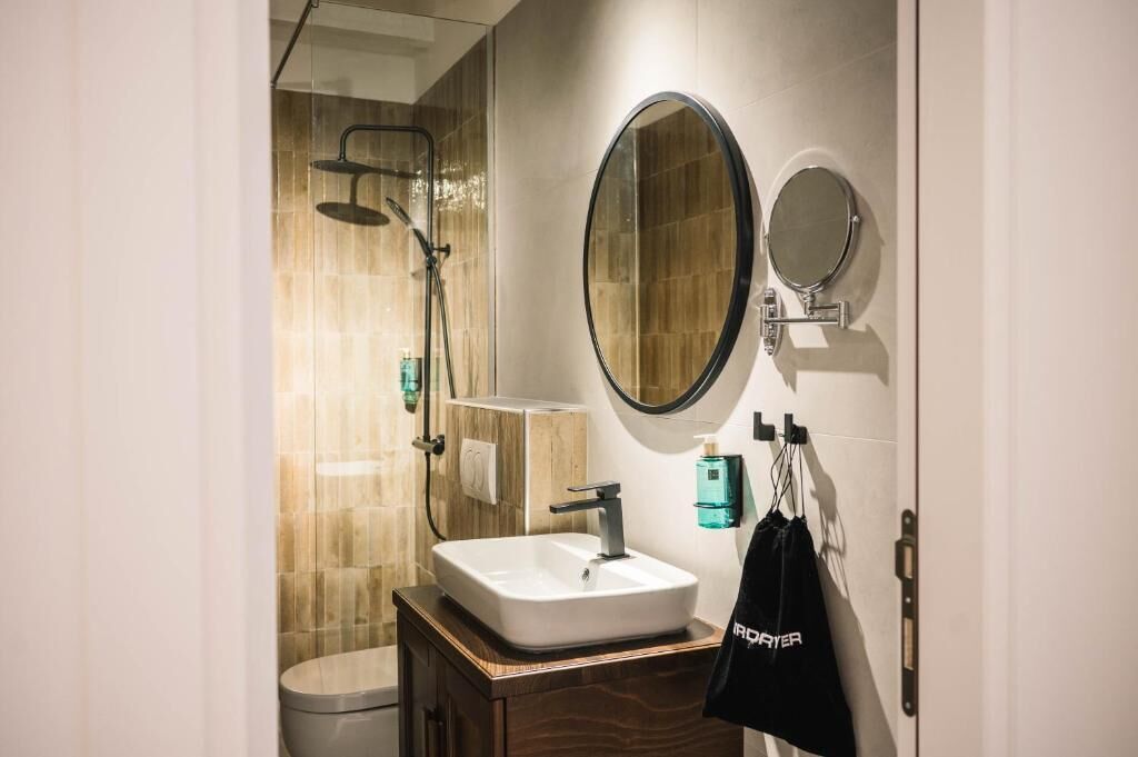 A modern bathroom with a shower, a sink, and two mirrors.