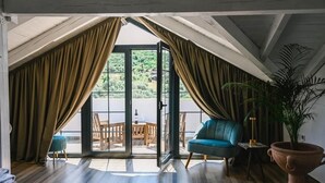 Une pièce dotée d’une grande porte-fenêtre coulissante, d’une chaise bleue, d’une table en bois et d’une plante en pot.