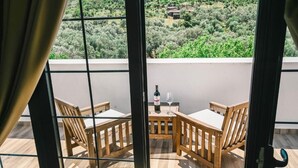 Un balcon avec deux chaises en bois, une table, une bouteille de vin et un verre.