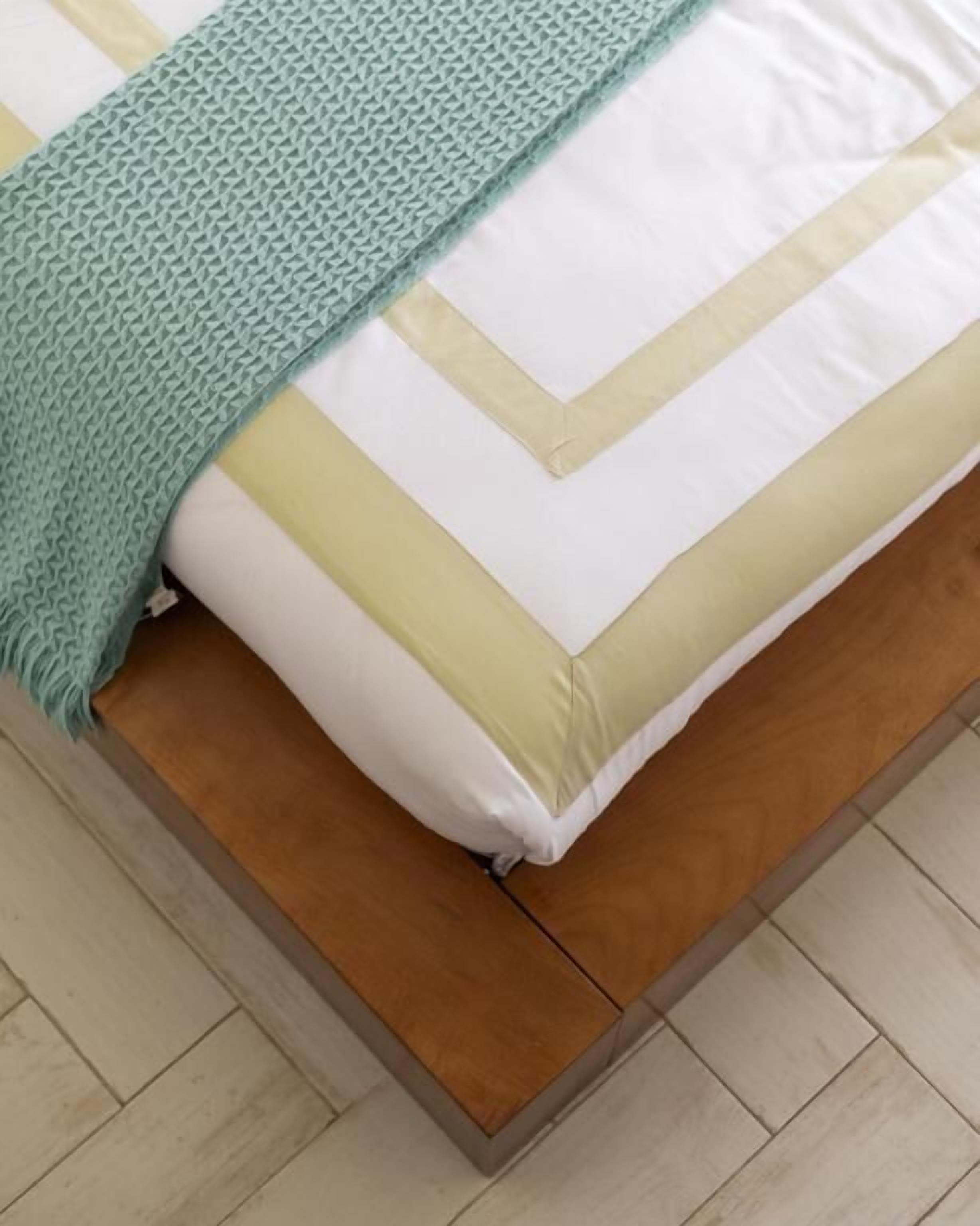 A bed with a wooden frame, a white and beige striped pillow, and a teal blanket.