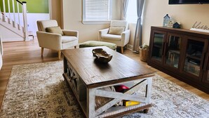 A living room with a wooden coffee table, two armchairs, a bookshelf, and a staircase. - Spacious 4-bedroom house in tranquil Grovetown (Grovetown)