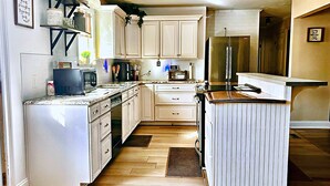 A kitchen with white cabinets, a refrigerator, a microwave, and a coffee maker. - Spacious 4-bedroom house in tranquil Grovetown (Grovetown)