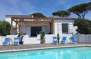 Ett område vid poolen med en pergola, utomhusmöbler och en pool.
