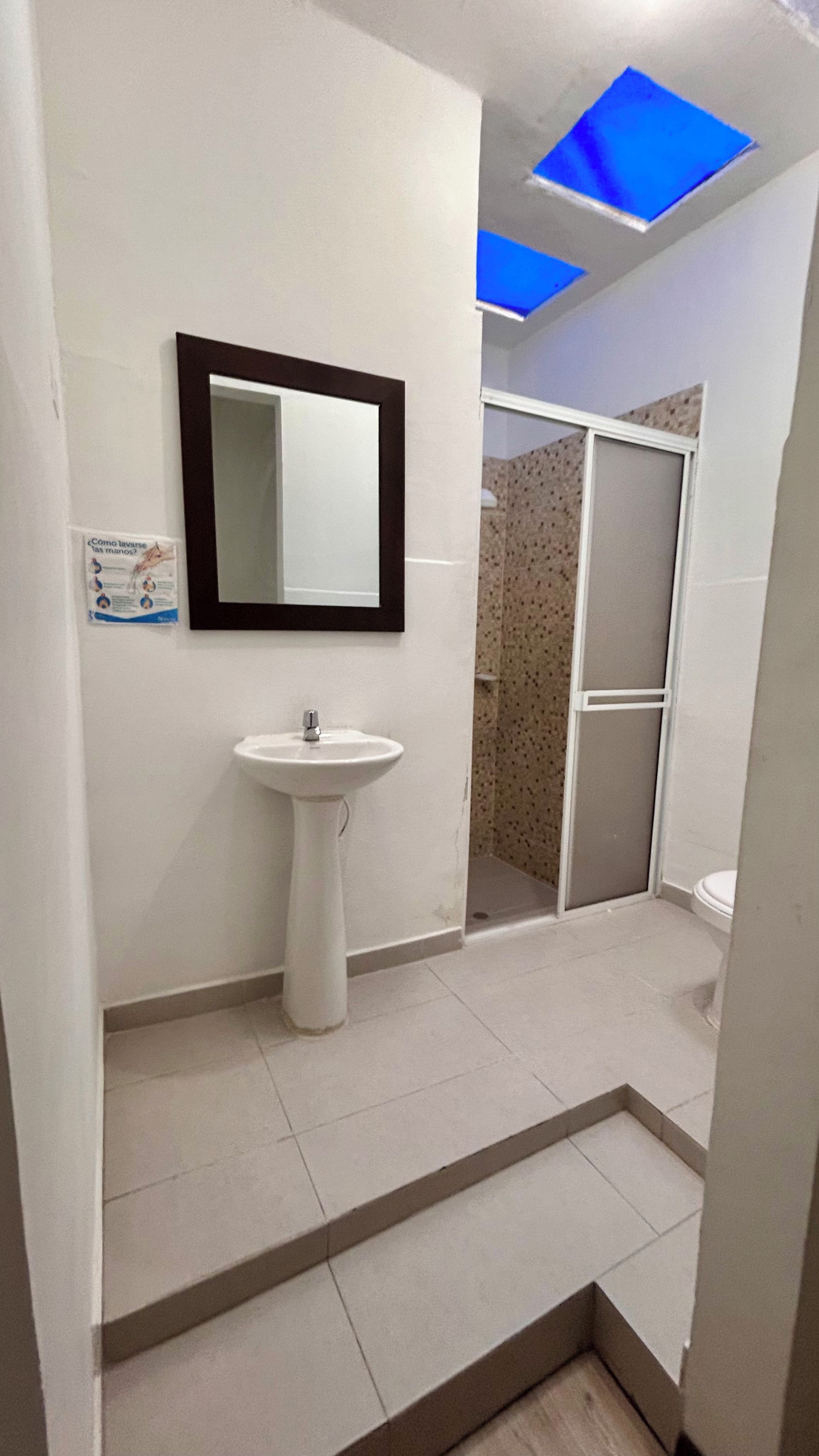 A bathroom with a white sink, a mirror, and a shower area.