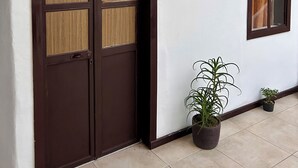 A hallway with a wooden door with glass panels, a framed picture on the wall, and potted plants. - Hotel Santa Marta's (Popayán)