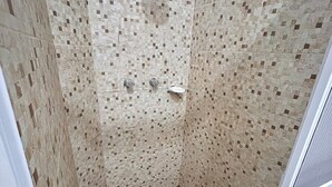 Una doccia con pareti in mosaico e pavimento bianco.