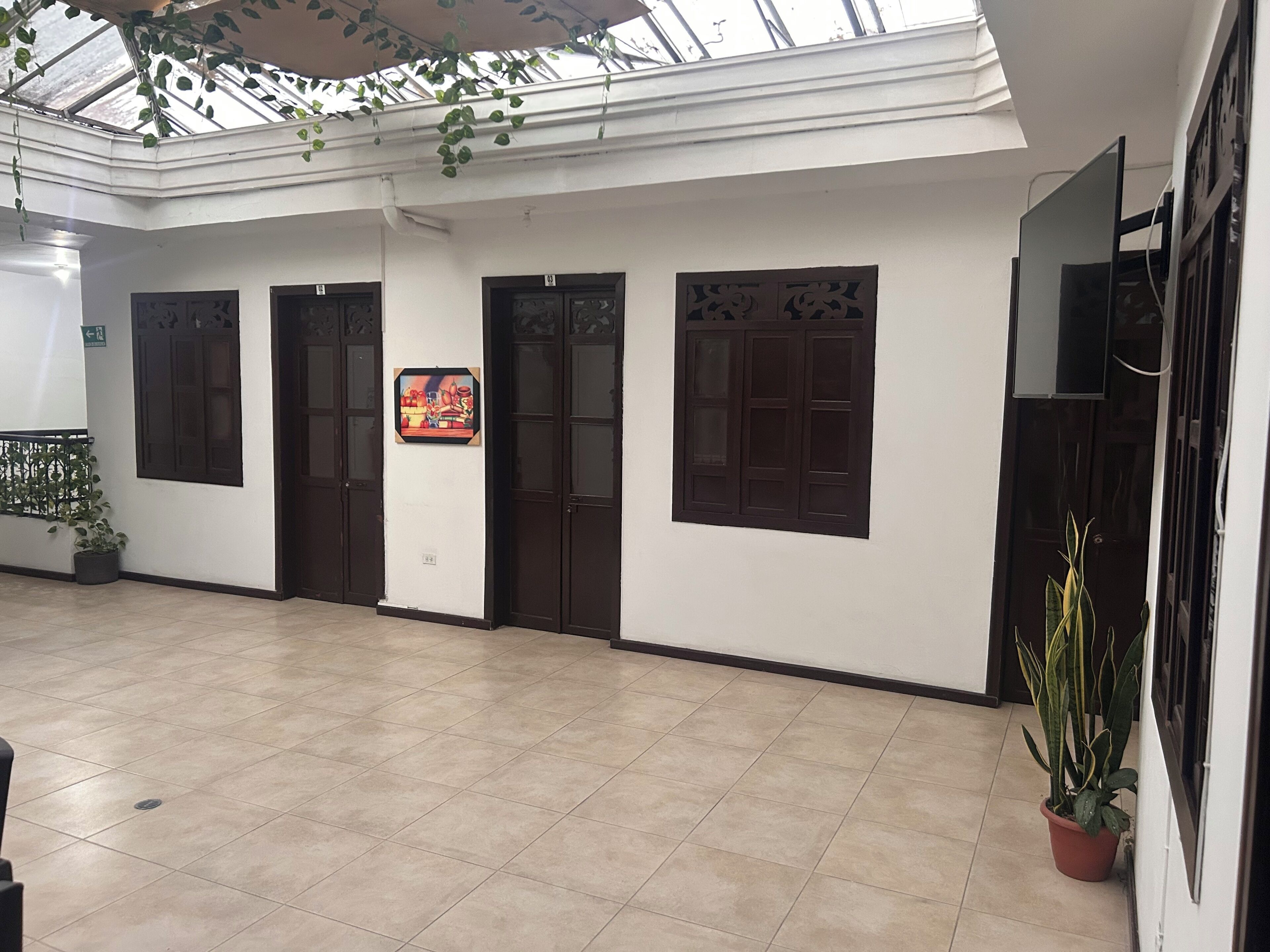 Un pasillo con suelo de baldosas, puertas de madera oscura y un techo con tragaluz.