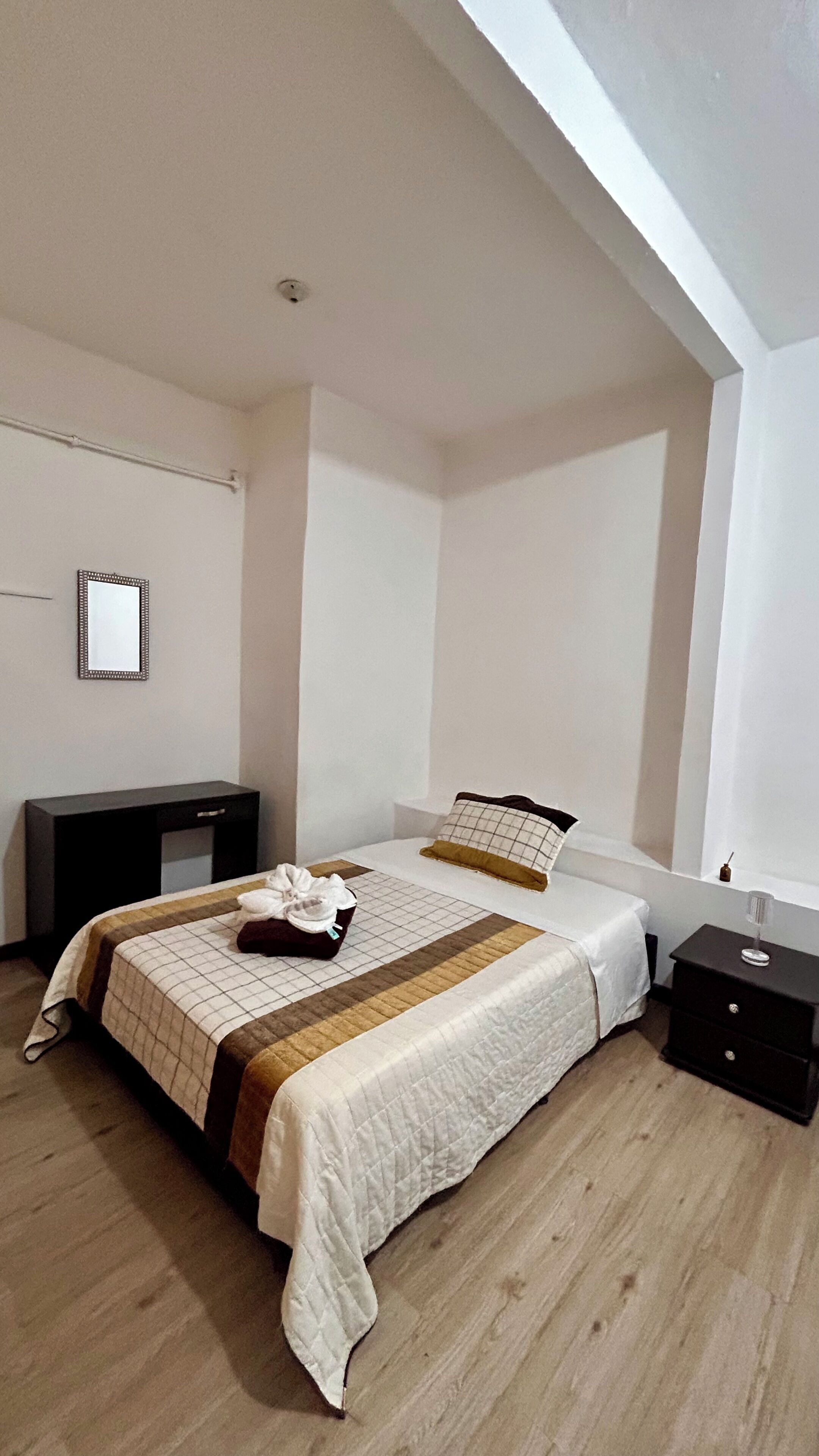 Une chambre à coucher avec un lit, des tables de chevet, un miroir et une armoire.
