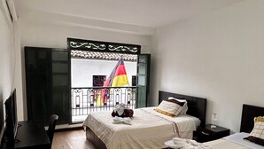 A hotel room with two beds, a desk, and a balcony with a view. - Hotel Santa Marta's (Popayán)