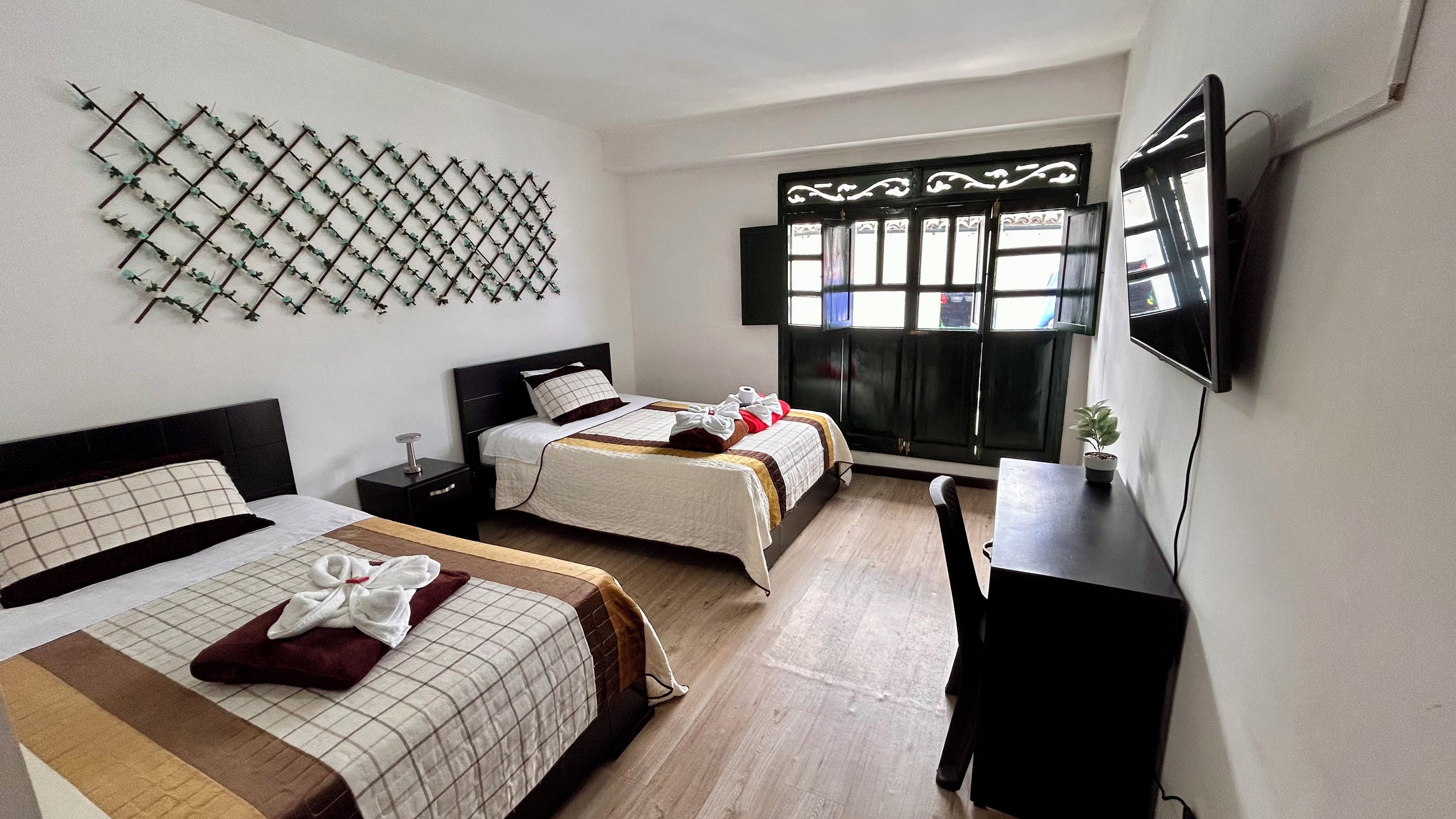 Habitación de hotel con dos camas, un escritorio, un televisor y un adorno en la pared.