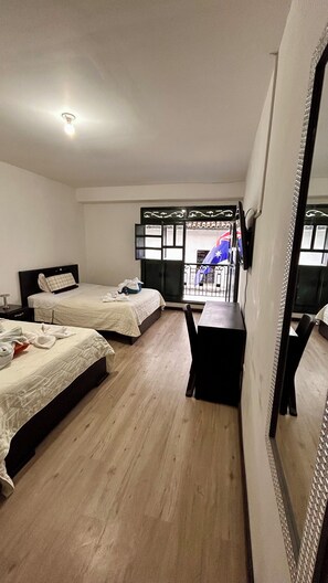 A hotel room with two beds, a desk, a chair, a large mirror, and a window with a view of the street. - Hotel Santa Marta's (Popayán)