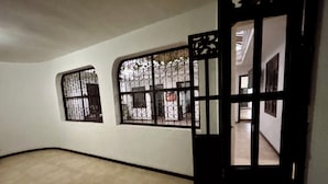 An interior hallway with tiled flooring, two windows with decorative iron grilles, and a partially open door. - Hotel Santa Marta's (Popayán)