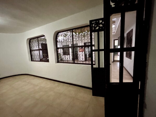An interior hallway with tiled flooring, two windows with decorative iron grilles, and a partially open door. - Hotel Santa Marta's (Popayán)