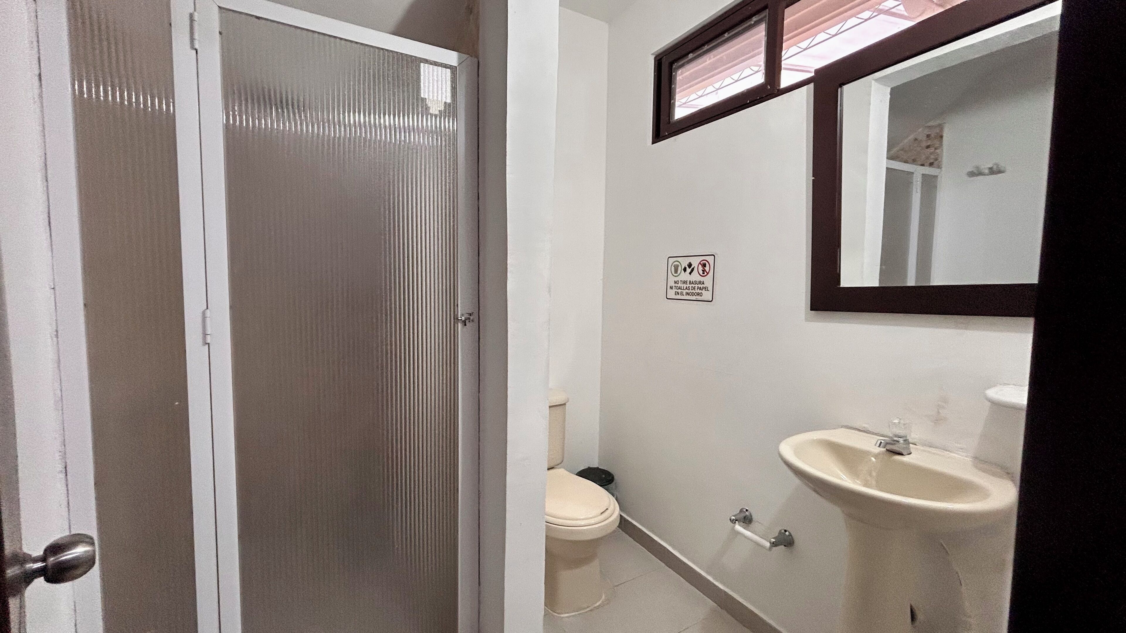 A bathroom with a toilet, sink, and mirror.