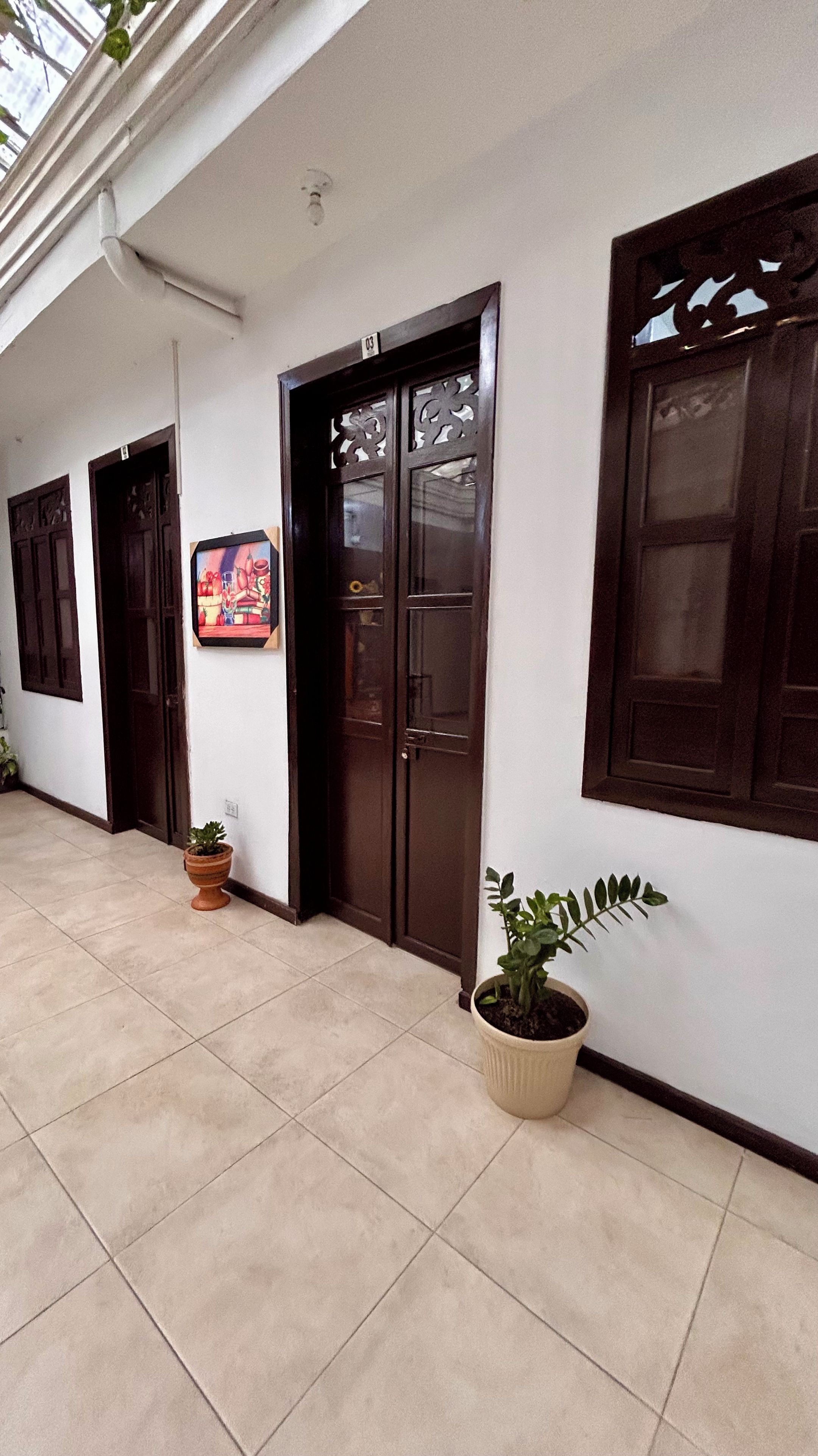 A hallway with a tiled floor, a potted plant, and a door with a number sign.