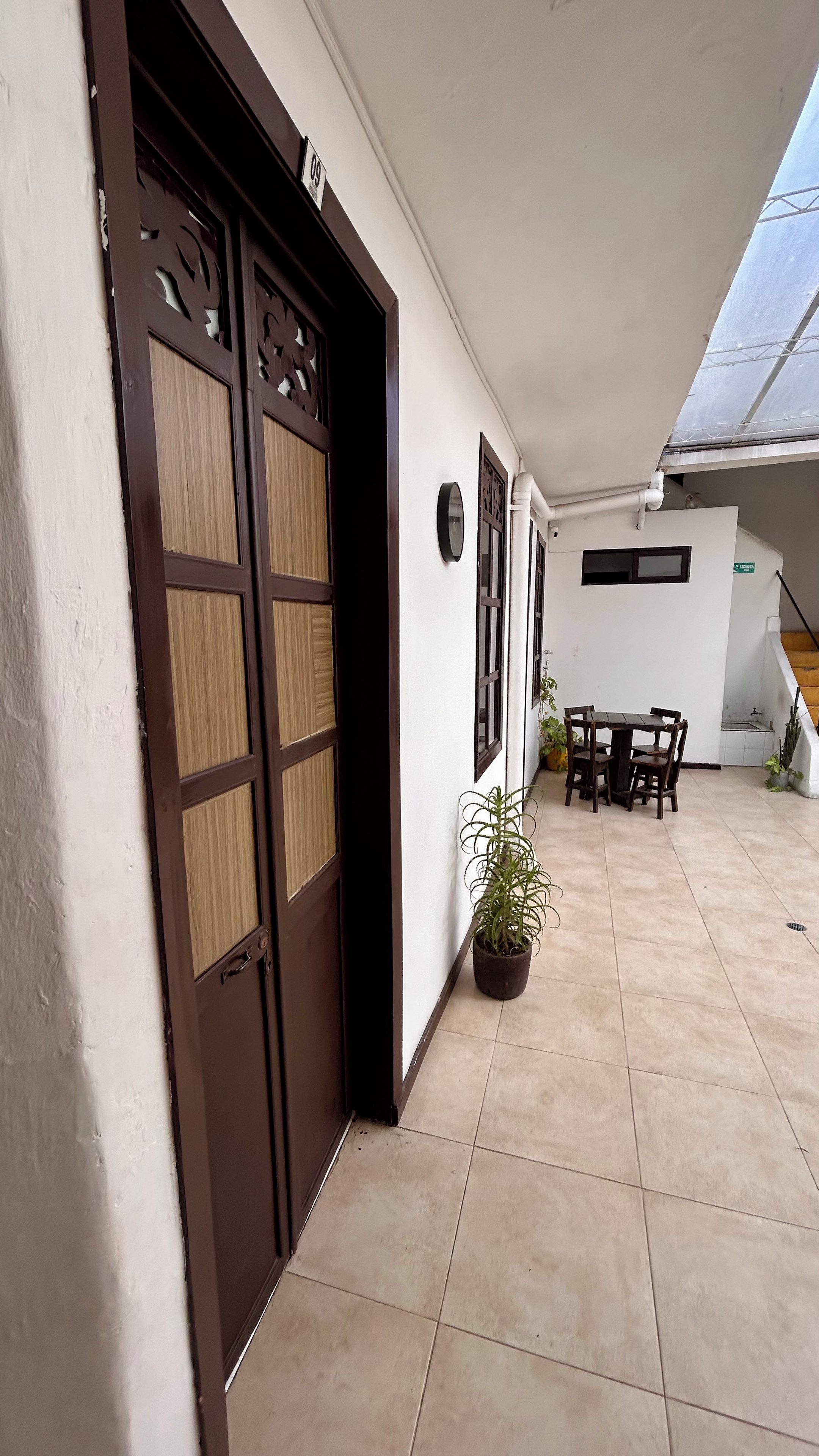 Un couloir avec une double porte, un coin repas avec une table et des chaises, et une plante en pot.