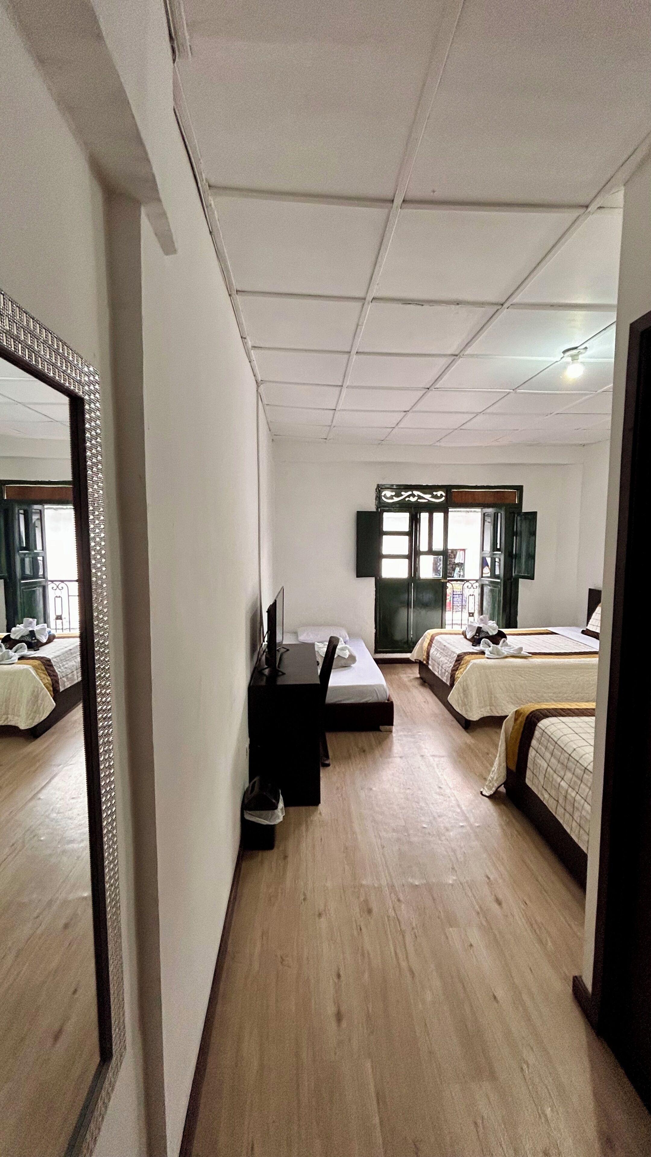 Ein Hotelzimmer mit Schreibtisch, zwei Betten, einem Spiegel und einem Fenster mit Blick.