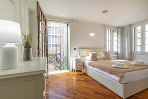 Ein Schlafzimmer mit Bett, Nachttisch, Lampe und Blick ins Freie.