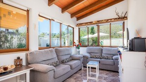 A living room with two grey sofas, a small table, a TV, and a cabinet. - Villa Luna with Pool and Mountain Views (Alcúdia)