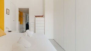 Ein modernes Hotelzimmer mit einem Bett, einem Schrank, einem kleinen Tisch und einer Tür zu einem Badezimmer.