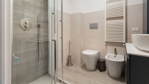 Ein modernes Badezimmer mit Duschkabine aus Glas, Toilette, Bidet und Waschbecken.