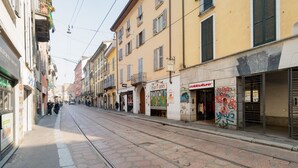 Eine Straße mit Gebäuden, einer Straßenbahnschiene und einigen Fußgängern.
