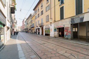 A street with buildings, a tram track, and a few pedestrians. - GuestHost - Cozy 40m2 apartment, ideal for two, on the third floor of a building with lift.The accommodation is located a stone's throw from Piazza Vetra, a historic district of Milan, located behind the Basilica of San Lorenzo, transformed from a popula (Milan)