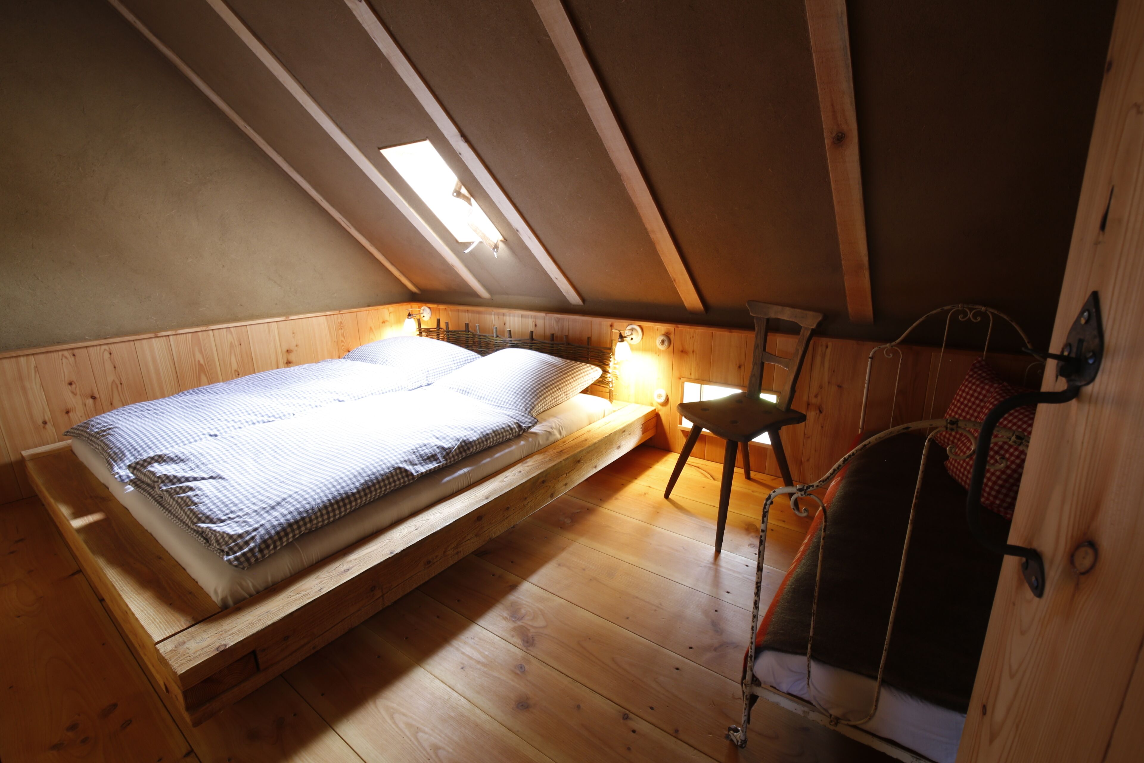 Un dormitorio tipo loft con una cama nido de madera, un escritorio pequeño y una silla.