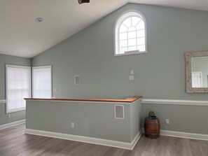 A room with a sloped ceiling, a large window, a wooden bench, a round copper table, and a mirror on the wall. - Relaxing 1BR Oasis with Dreamy Spa Bathroom (Wilmington)