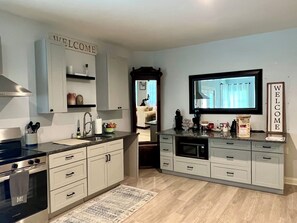 A modern kitchen with white cabinetry, a built-in oven, and a coffee machine. - Relaxing 1BR Oasis with Dreamy Spa Bathroom (Wilmington)