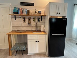 A kitchen with a wooden countertop, a black refrigerator, white cabinets, and a shelf with books and a decorative pitcher. - Relaxing 1BR Oasis with Dreamy Spa Bathroom (Wilmington)