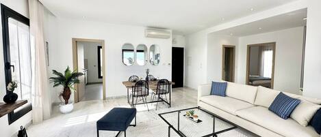 A modern living room with a sofa, coffee table, and dining area.