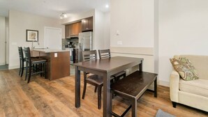 Eine moderne Küche mit dunklen Holzschränken, einer zentralen Kochinsel und einem Essbereich mit Holztisch und Stühlen.