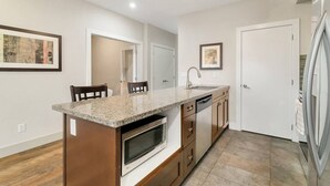 Eine moderne Küche mit Granit Arbeitsplatten, einem Einbauofen und einem Edelstahl-Kühlschrank.