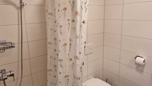 A bathroom with a shower, toilet, and a towel rack.