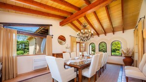 Ein Esszimmer mit Holzbalkendecke, großen Fenstern und einer Kristalllüster.
