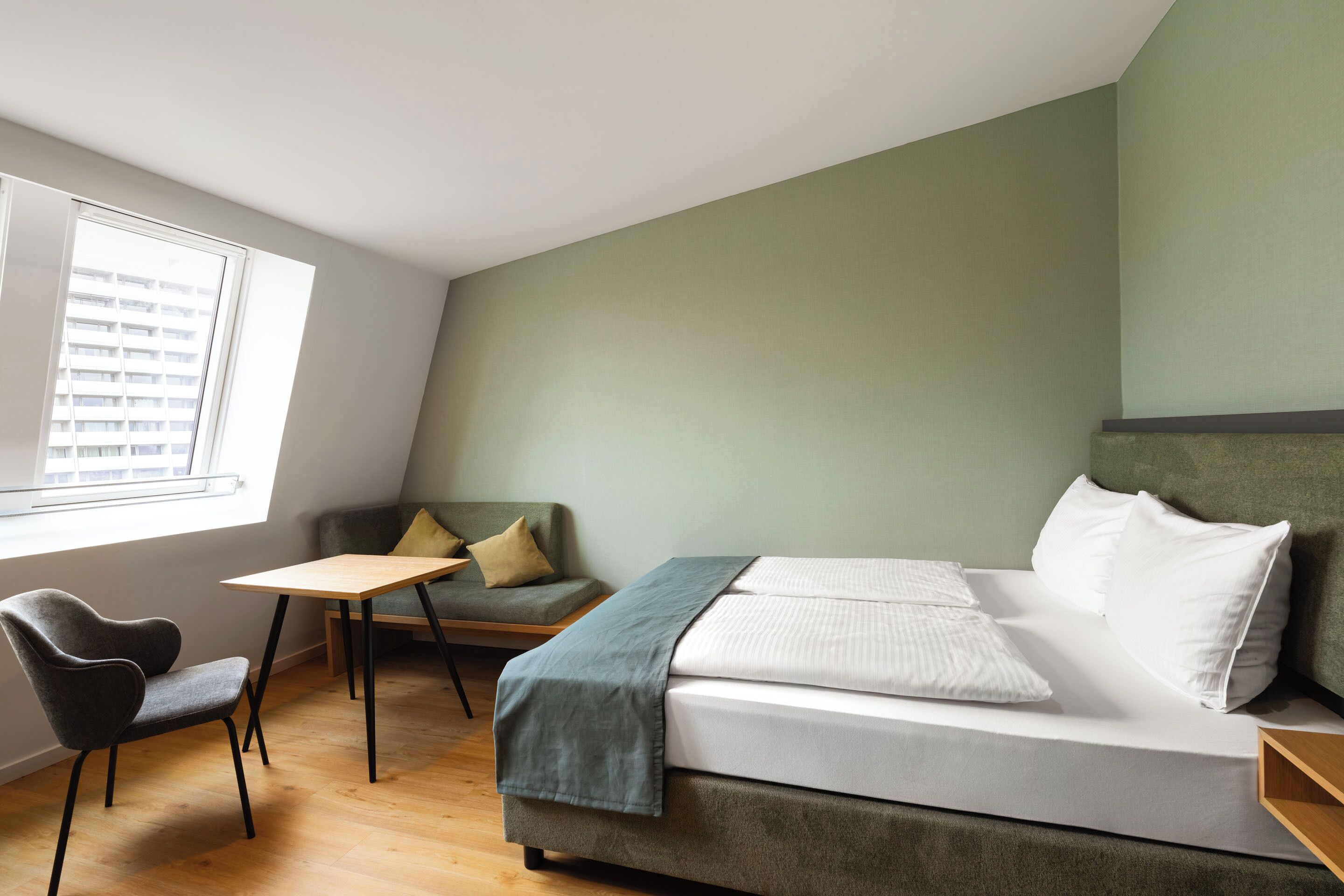 Una habitación con una cama, una silla, una mesita y una ventana con persianas.