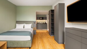 A modern hotel room with a bed, a TV, a kitchenette, and a wooden floor. - Limehome Munich Theresienwiese (Munich)