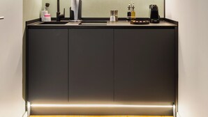 A compact kitchen with a built-in microwave, a sink, and a countertop with various kitchen items. - Limehome Munich Theresienwiese (Munich)