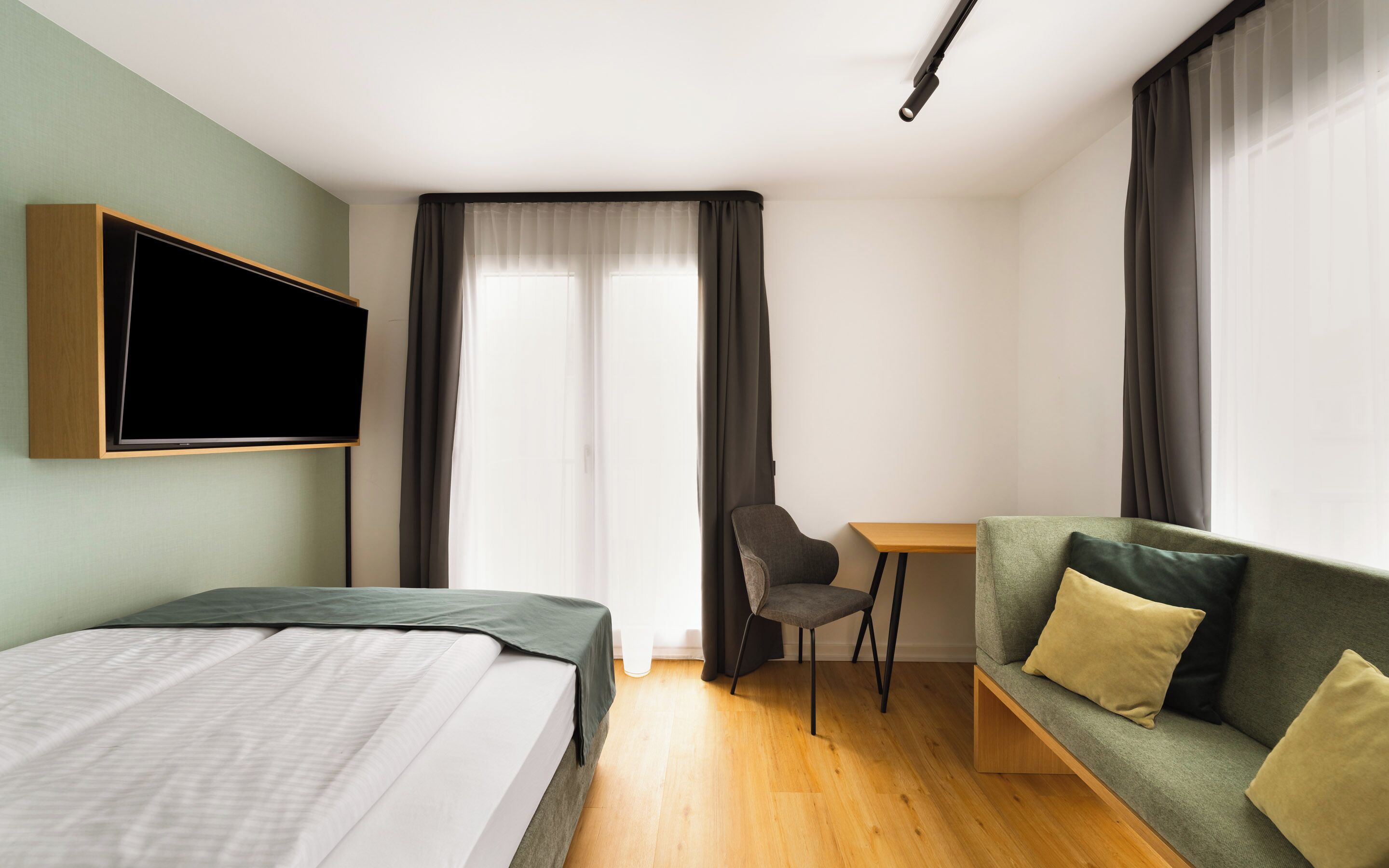 Una habitación de hotel con una cama, un sofá, un escritorio y un televisor.